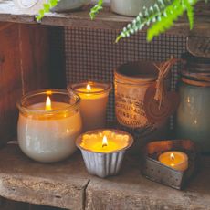 A group of lit scented candles on a rustic shelf