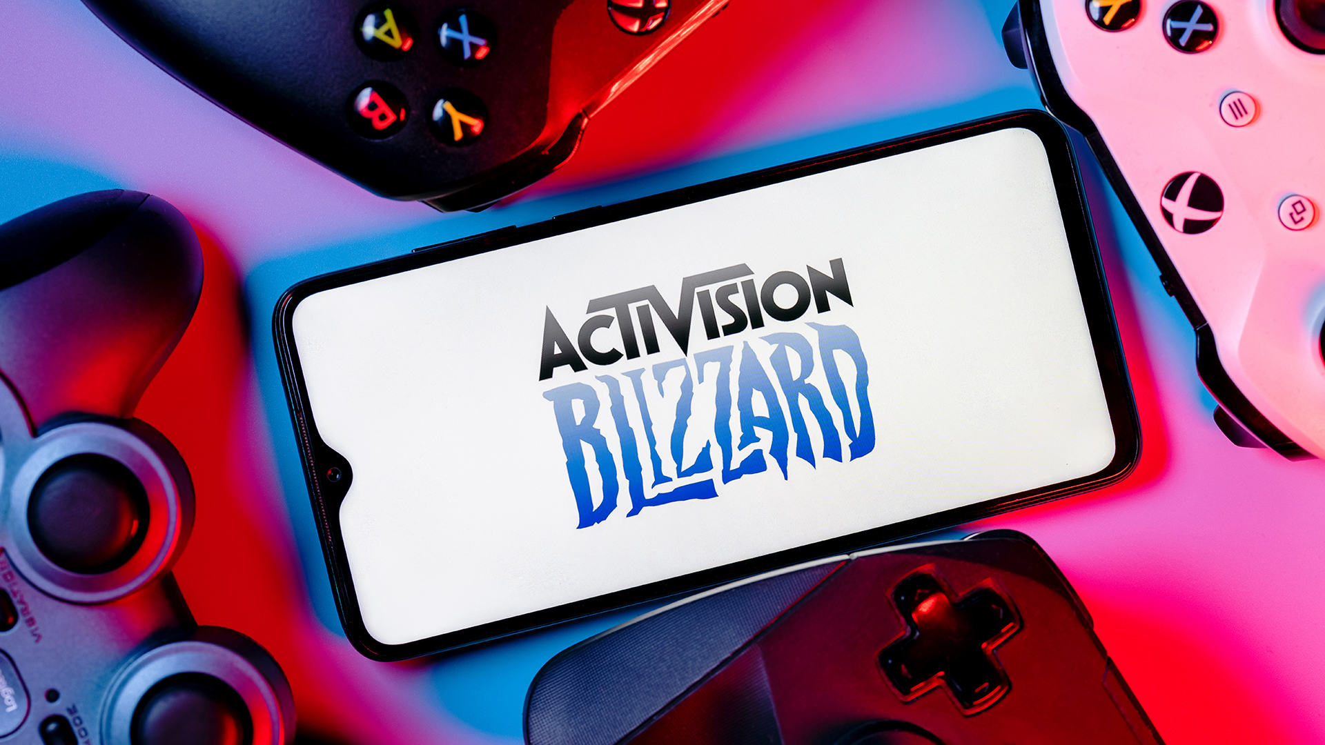 Activision Blizzard logo on a smartphone surrounded by games controllers