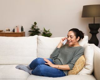 Woman on sofa talking on a BT landline phone