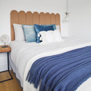White bedding with blue throw and cushions with brown headboard