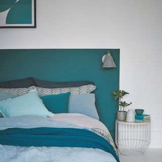 bedroom with double bed with green and grey bedding painted green headboard