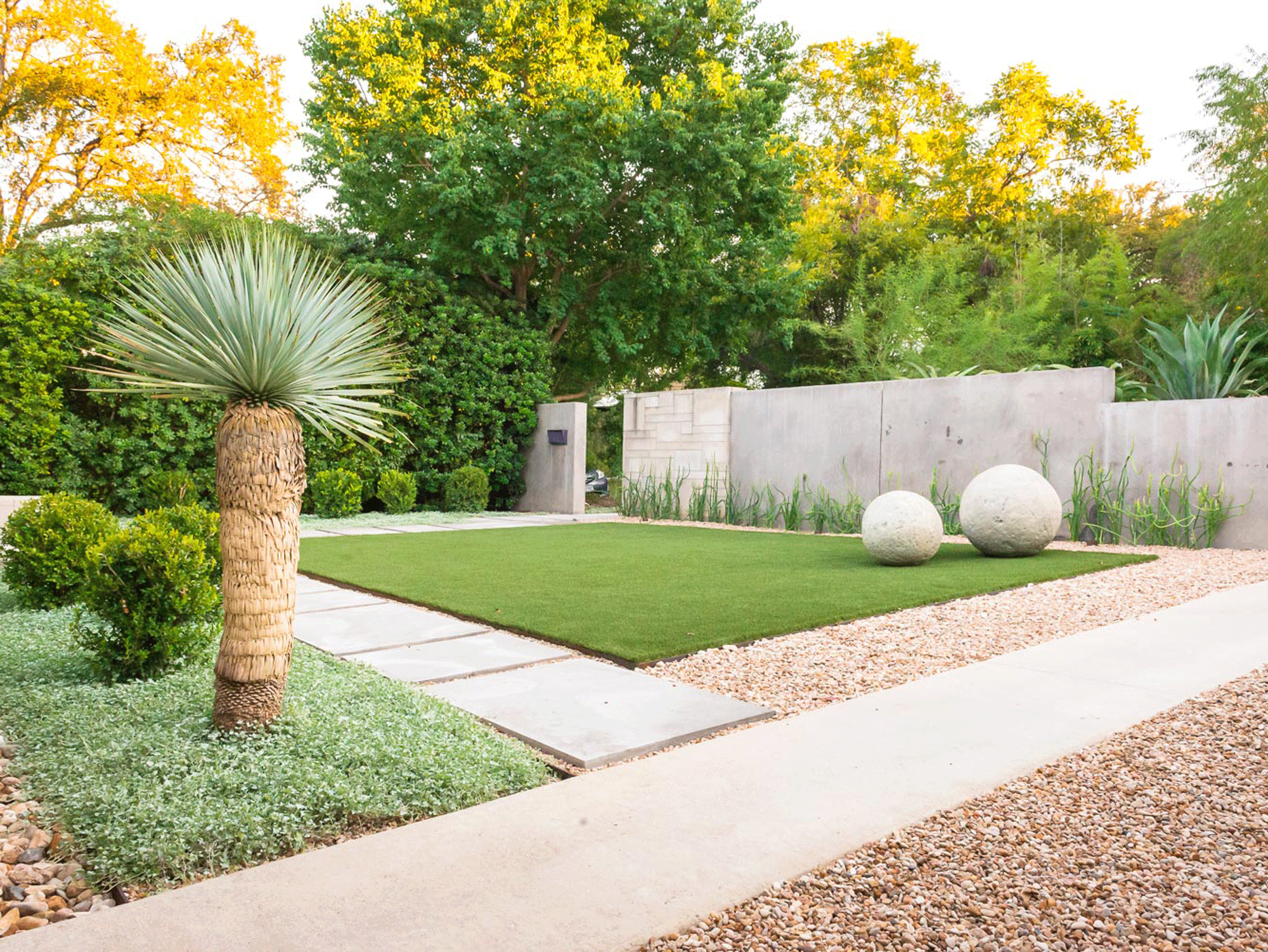 modern backyard with lawn, gravel, planting and stone sculpture