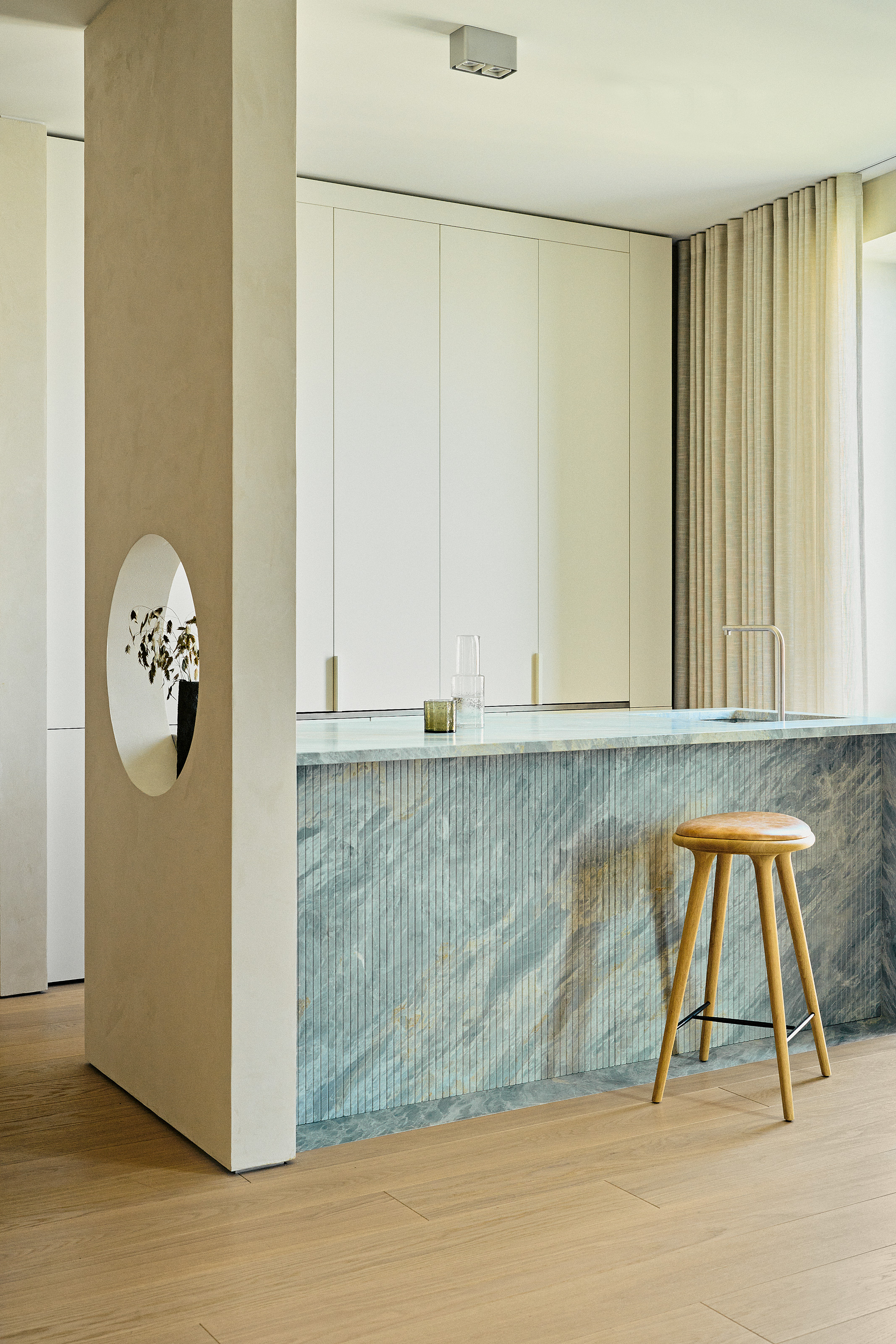 Kitchen with cream minimalist units and blue stone island with fluted detailing
