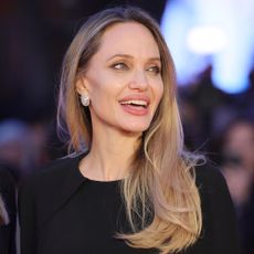 Angelina Jolie smiles wearing a black dress on the red carpet
