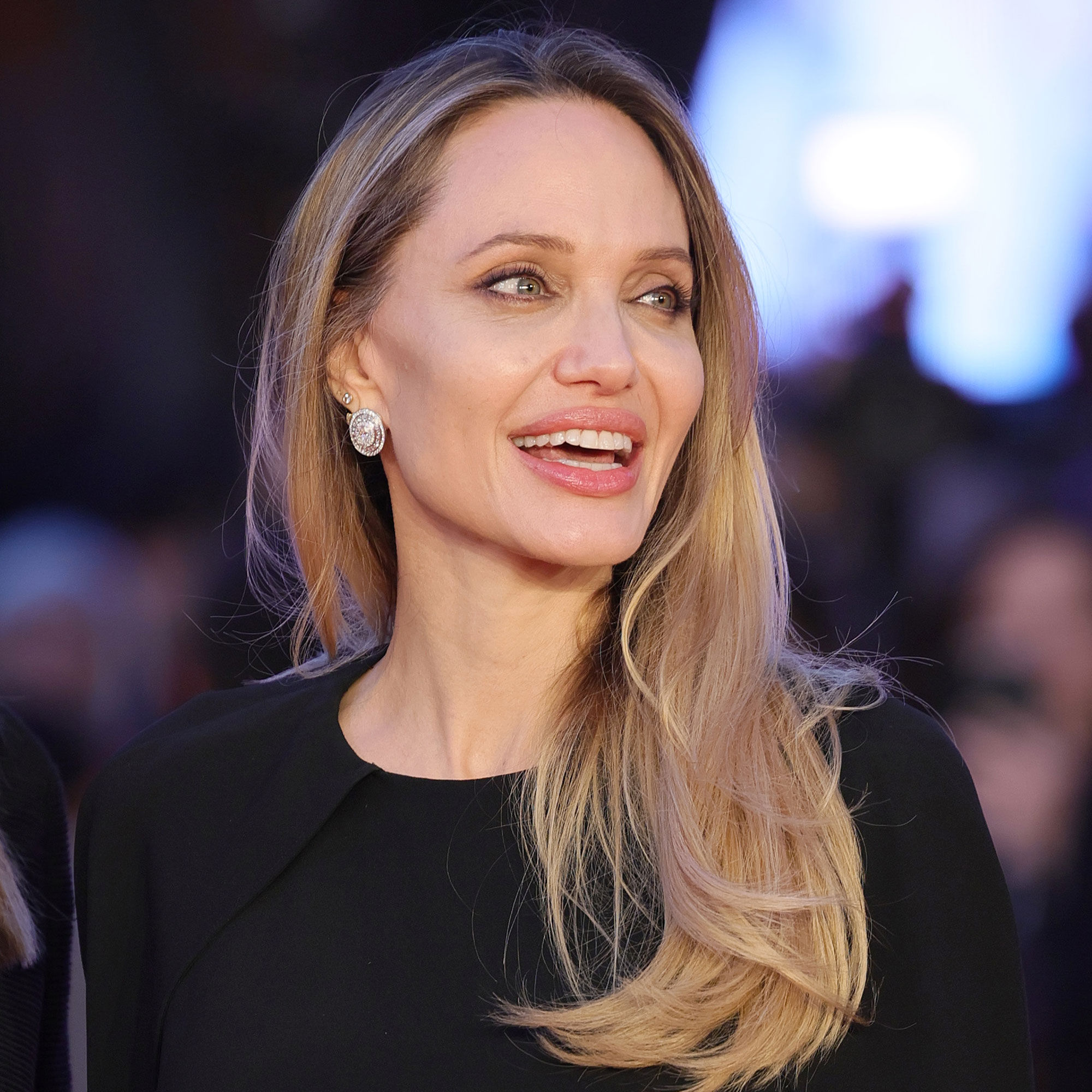 Angelina Jolie smiles wearing a black dress on the red carpet