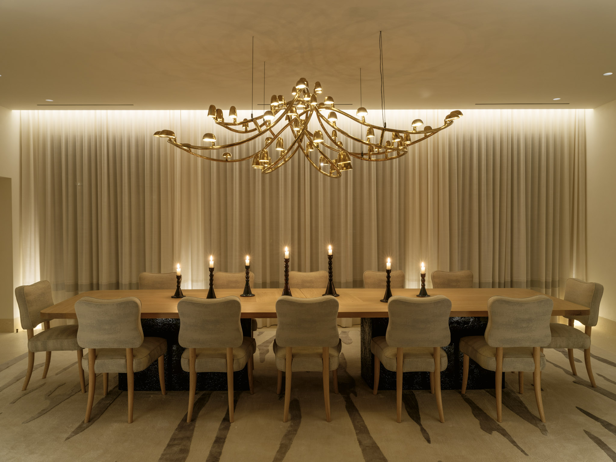 Theatrical interiors with art installation-like ceilings, a consistent yet striking palette, statement lighting in bold forms, and softly shaped furniture.
