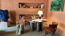 Mid-century-style living room featuring a chrome table, cobalt sculpture, and cork-covered walls