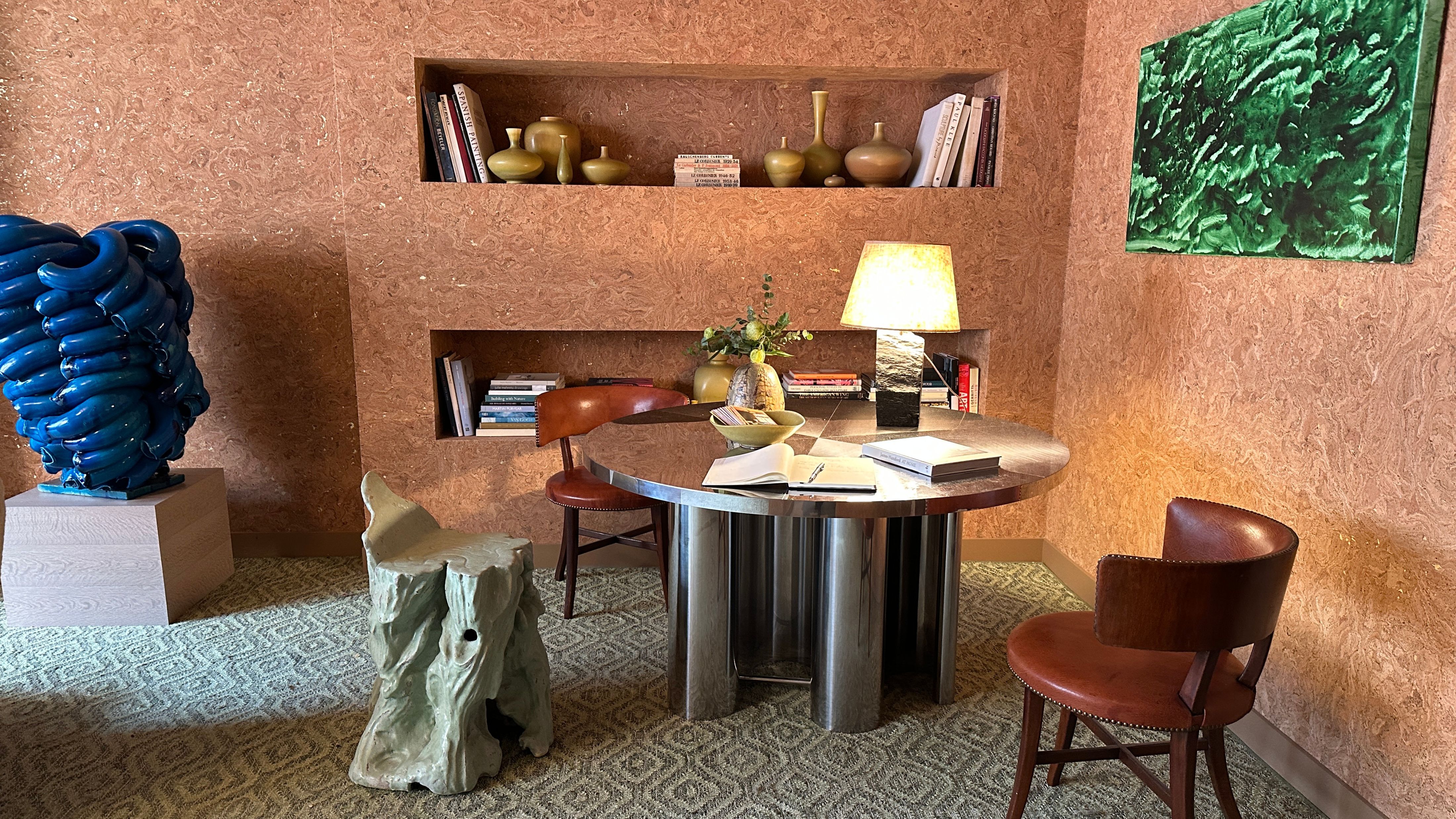 Mid-century-style living room featuring a chrome table, cobalt sculpture, and cork-covered walls