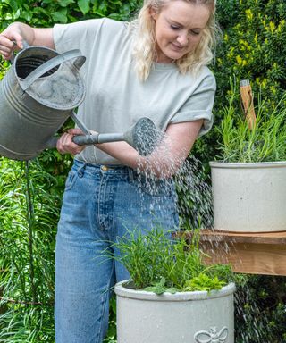 Woman watering a herb planter with a watering can
