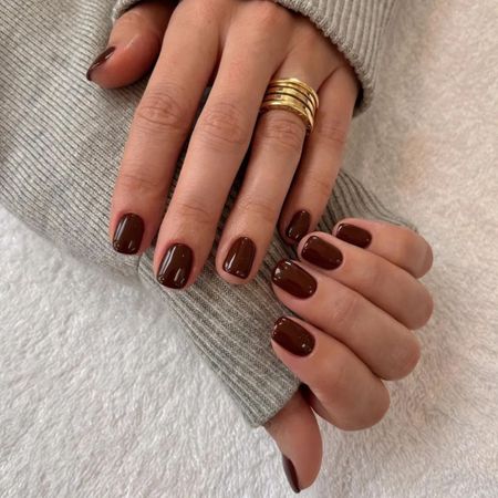 A woman wearing a grey jumper with a short, maroon manicure