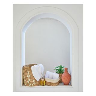 Cute woven baskets in curved alcove, filled with rolled white towels.