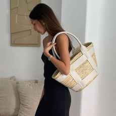 Woman wears black dress and carries white basket bag