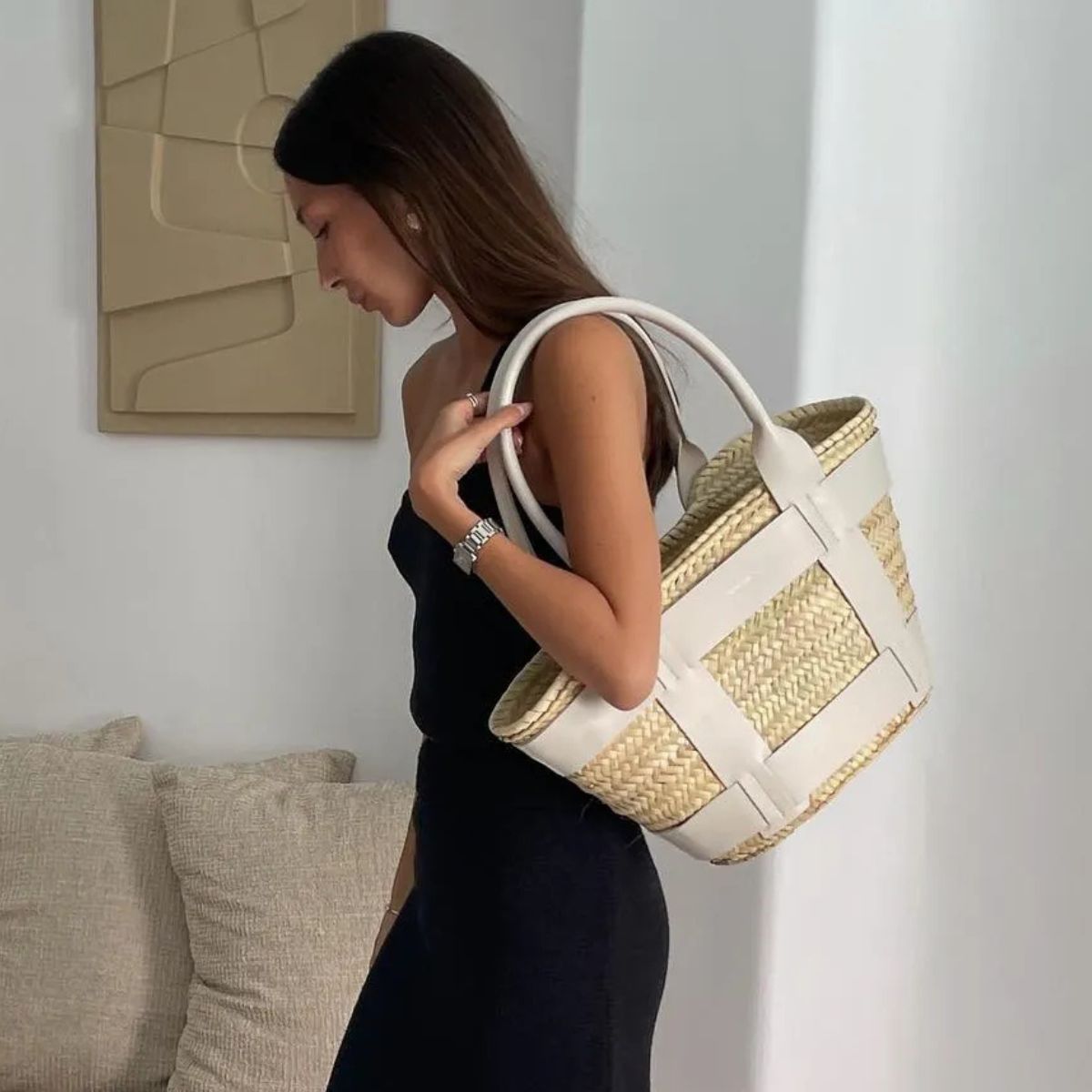 Woman wears black dress and carries white basket bag