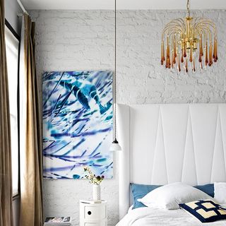 bedroom with white wall and bed with golden ceiling light
