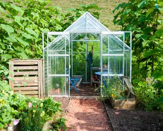 Garden greenhouse with compost bin and blue table and chair