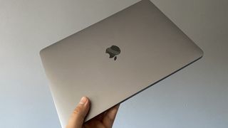 Apple M1 MacBook Pro 13-inch review: image shows hand holding the Apple M1 MacBook Pro 13-inch laptop