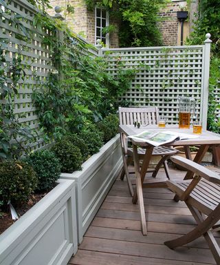 bistro set on decking with trellis fence and climbing plants