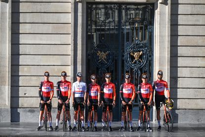 Team shot of the Ineos 2025 Tour de France building, the riders standing outside of a large building