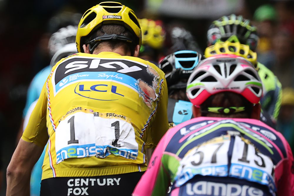 Chris Froome rides with a torn jersey near the end of stage 19.
