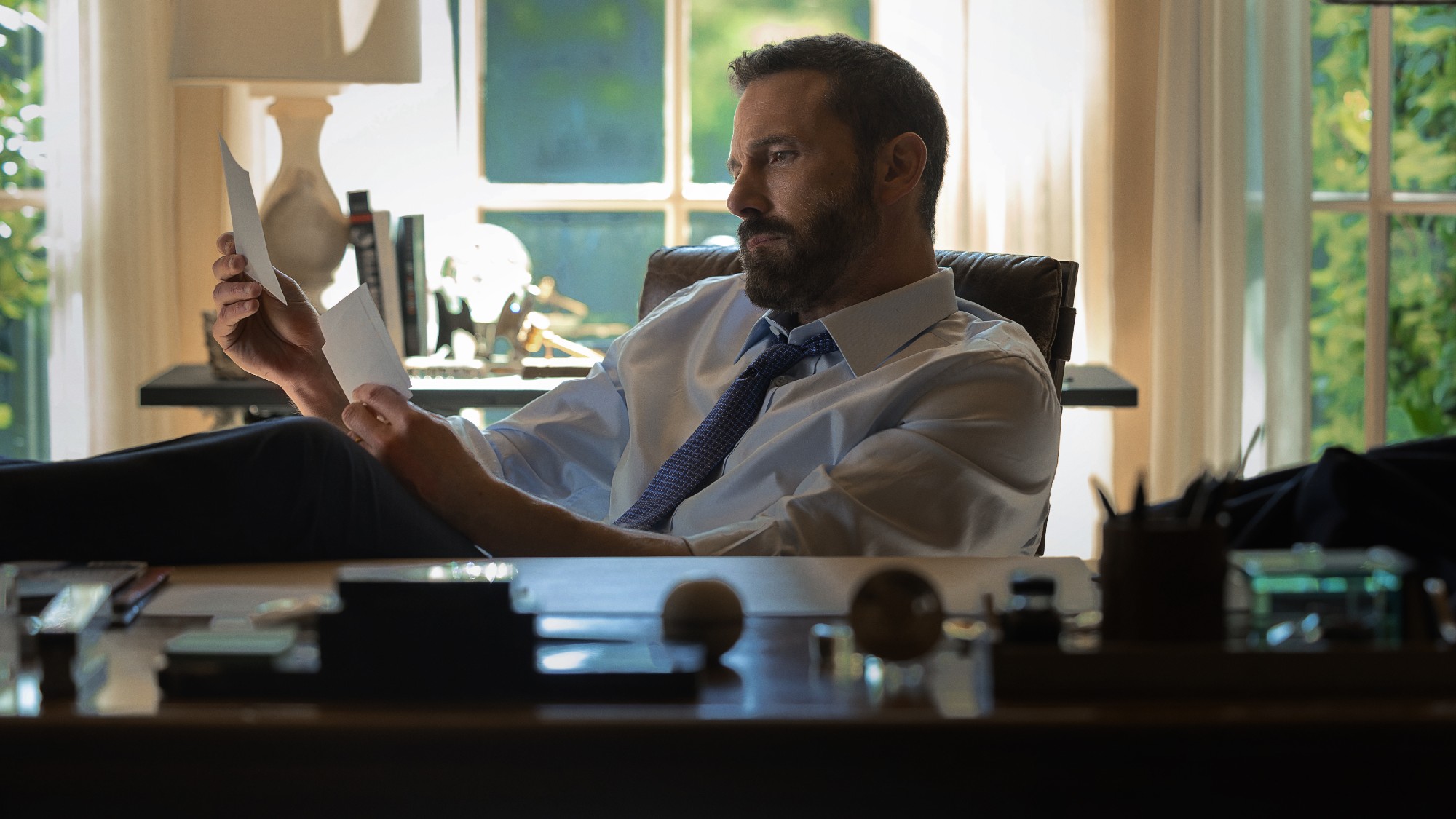 Mark Kimball (Ben Affleck) reads notes in his office and looks desperate in Animals.