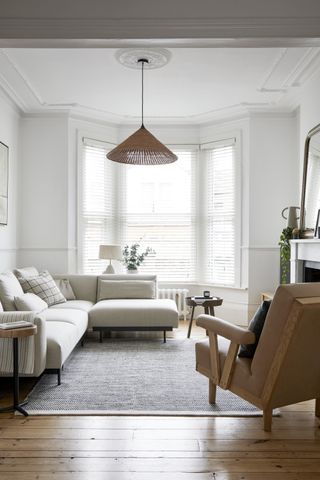 A L-shaped sofa with an armchair and a natural light hung above