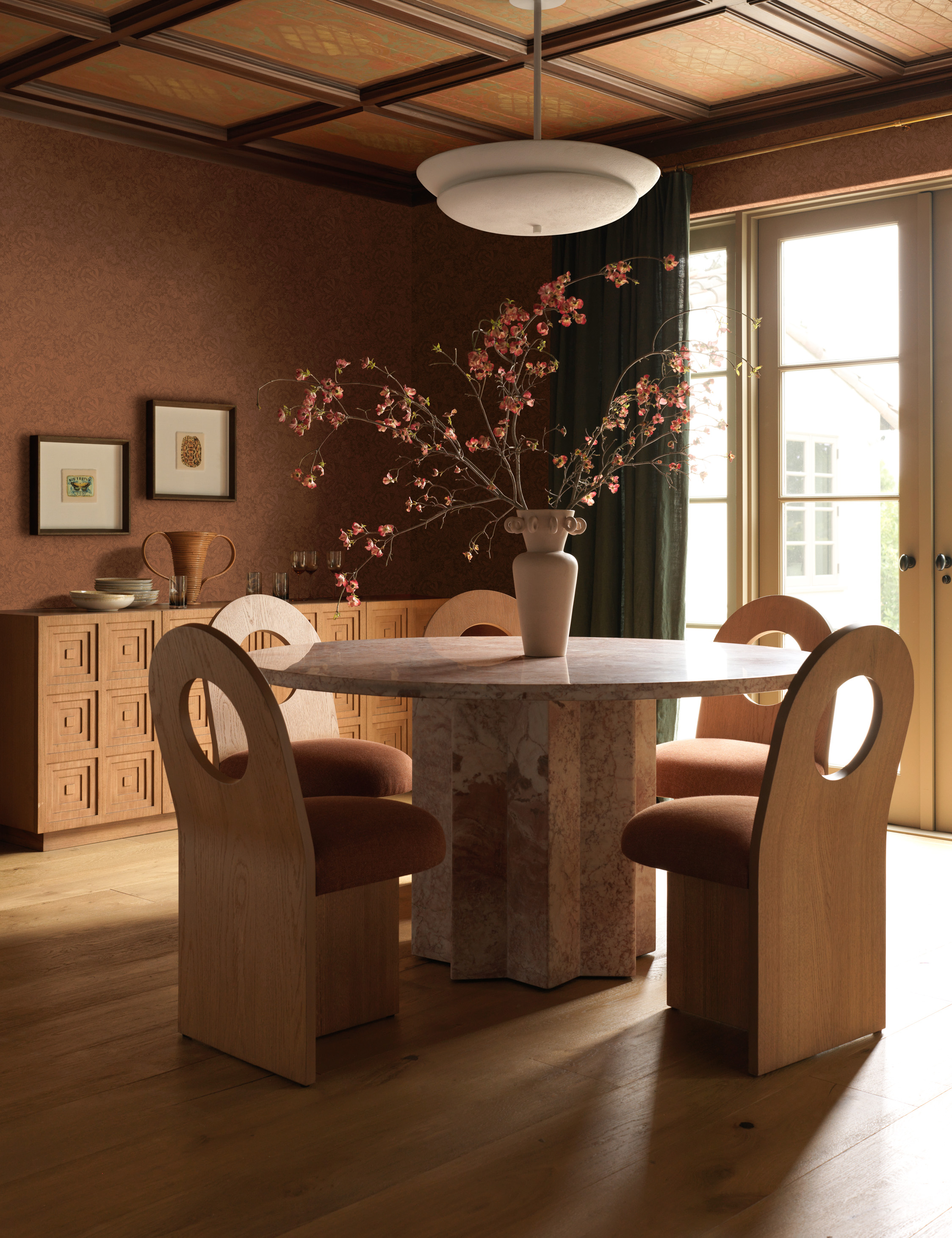 Dining room featuring a pink marble dining room table and five sculptural wooden dining chairs with circular back cutouts