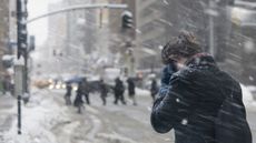 A stock image of a young woman walking through a snow storm.