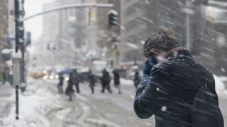 A stock image of a young woman walking through a snow storm.