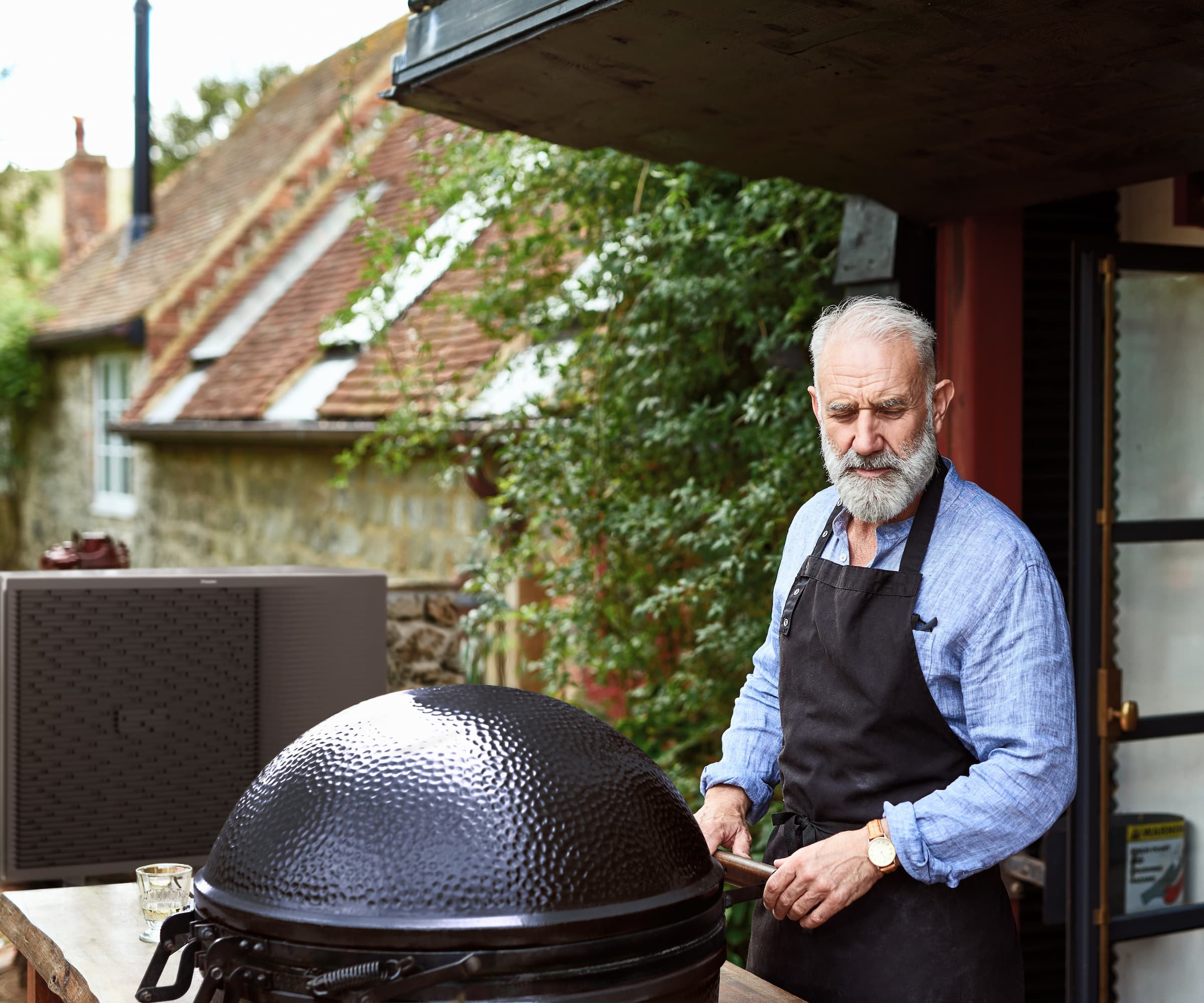 A Daikin heat pump next to a man using a barbeque