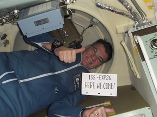 Italian astronaut Paolo Nespoli holds up a sign on Dec. 17, 2010 just before his Soyuz TMA-20 spacecraft arrives at the International Space Station during the Expedition 26/27 mission.