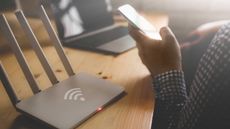 Best wi-fi extender: person on phone next to Wi-Fi box