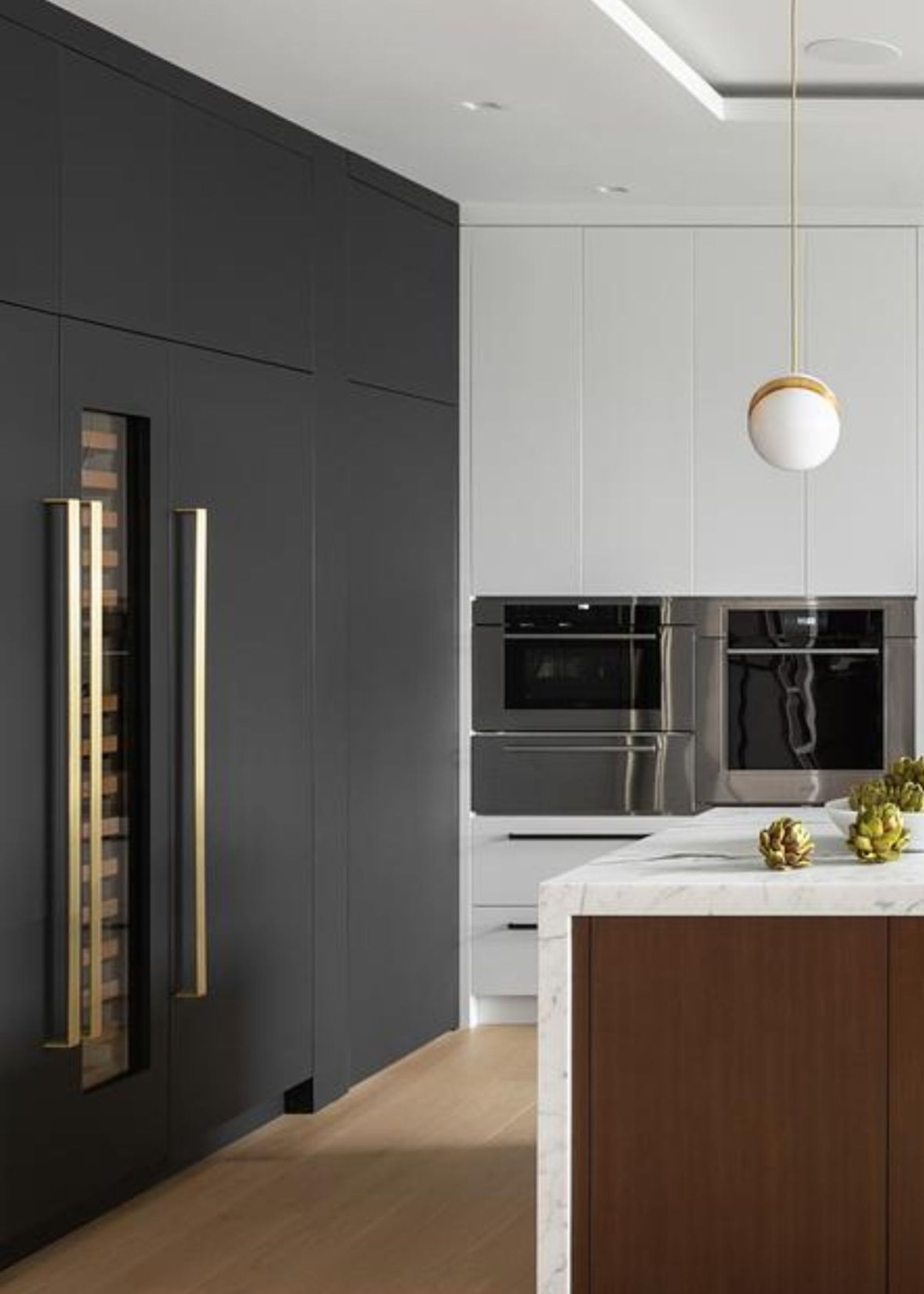 An oven with a proving drawer underneath as well as a microwave. There is also a corner view of the kitchen island with fruits on top