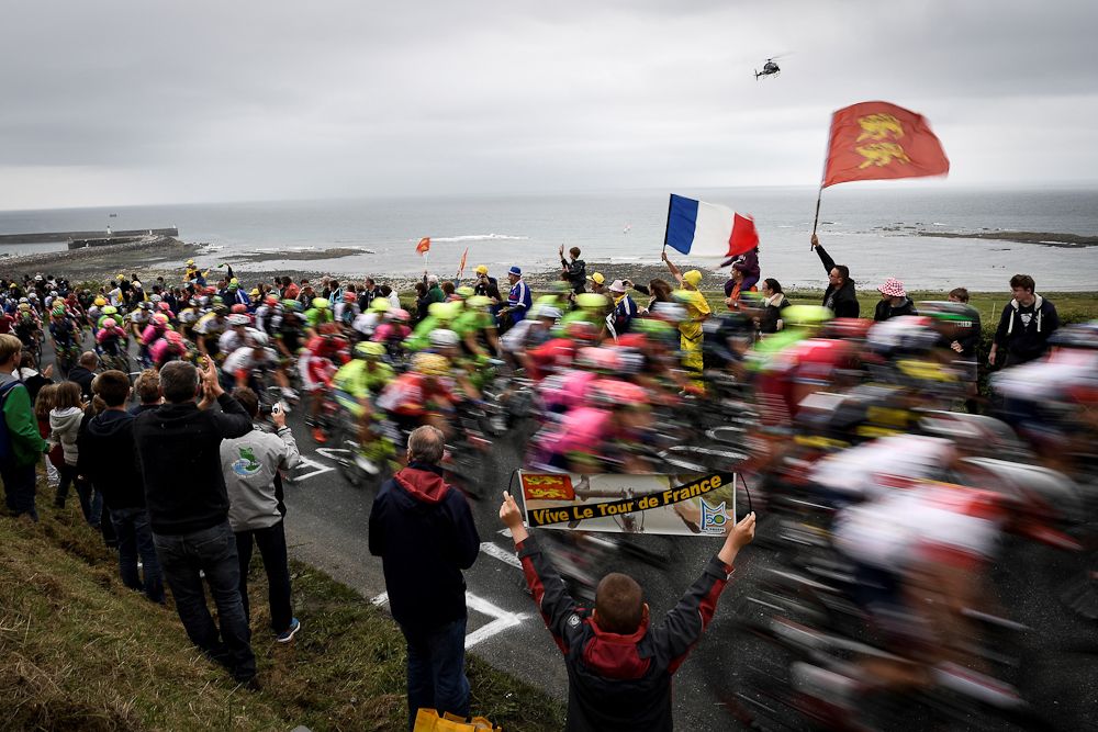 Fans watch the peloton speed along the coast