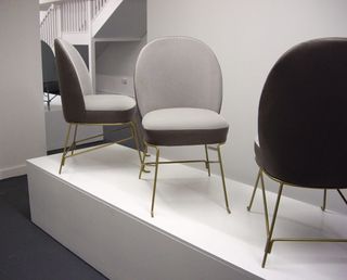 Three gray chairs with 4 thin metal legs photographed on a white platform