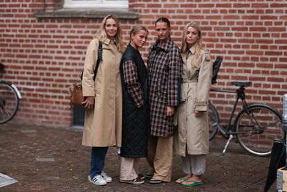 four women posing in trench coats