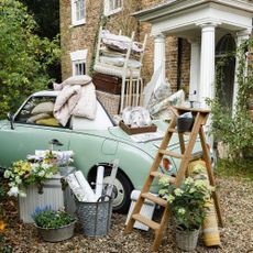 bricked house with blue car filled with items in front yard