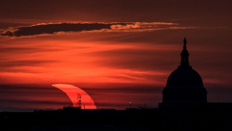 A partial solar eclipse seen at sunrise with the U.S. Capitol building on display in an image taken June 10, 2021, by NASA photographer Bill Ingalls.