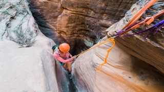 A climber rappelling into a slot canyon