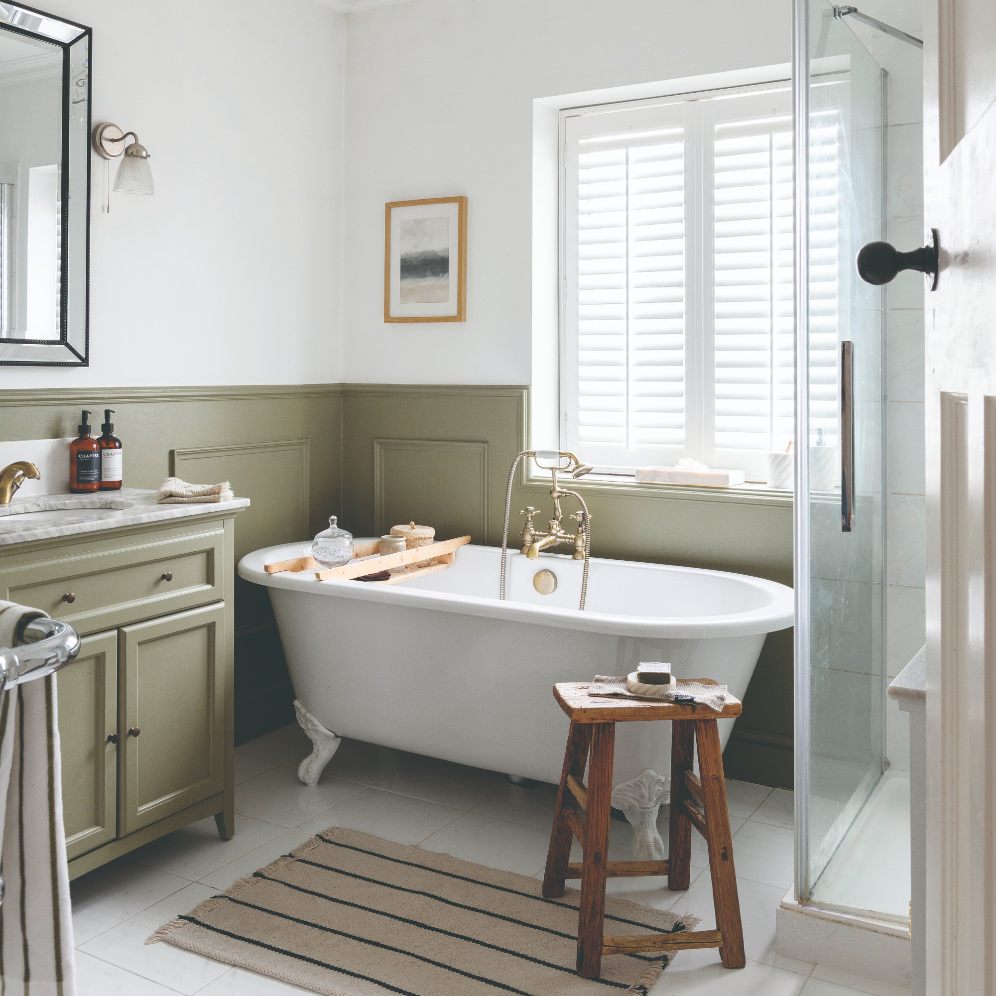 A bathroom with dado rail wall panelling painted in olive green and white window shutters