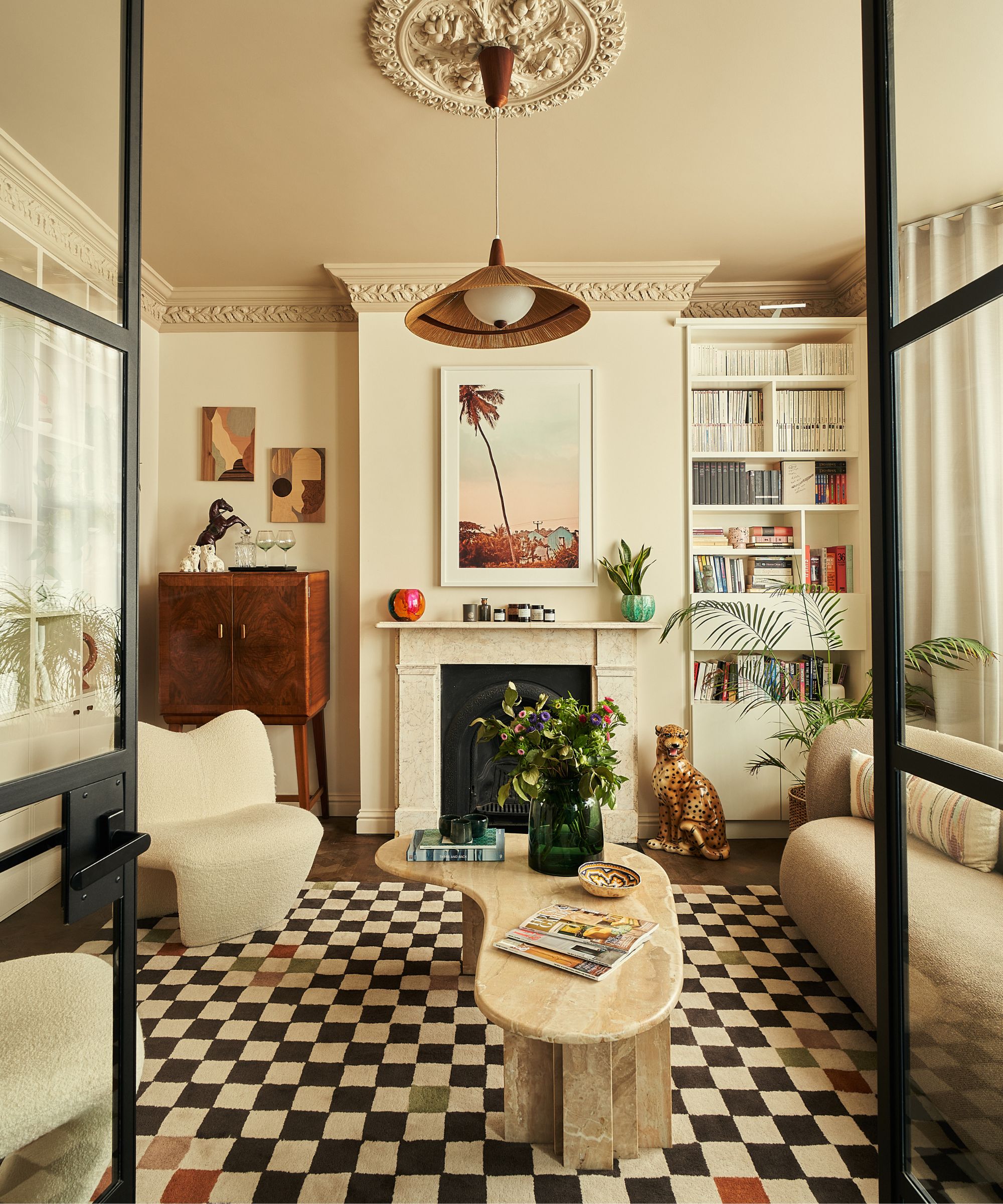 neutral living room with a painted warm yellow ceiling and coving, built in bookshelf vintage drinks cabinet and a marble fireplace