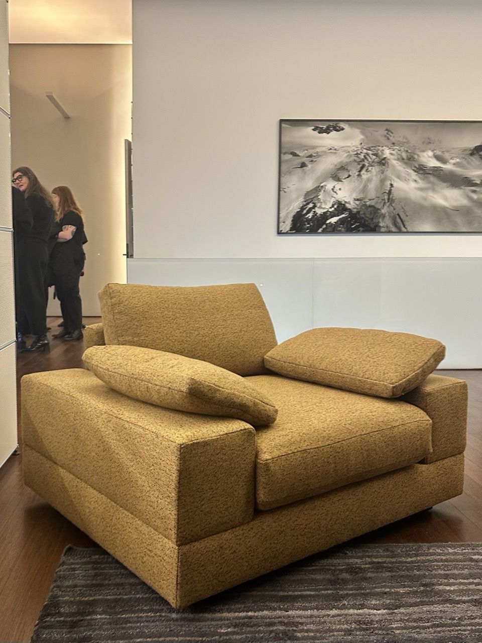 Plush, mustard color arm chair, with two pillows on either arm.