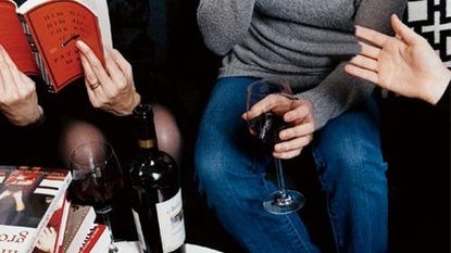 people around table with stacks of books and wine