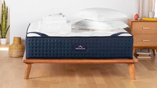 Best luxury mattress: DreamCloud mattress placed on a wooden bed frame in a white bedroom with wooden floors