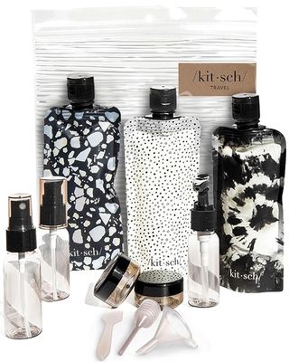 Three black and white flat bottles and two spray bottles and two small jars and one pump bottle in the Kitsch travel set