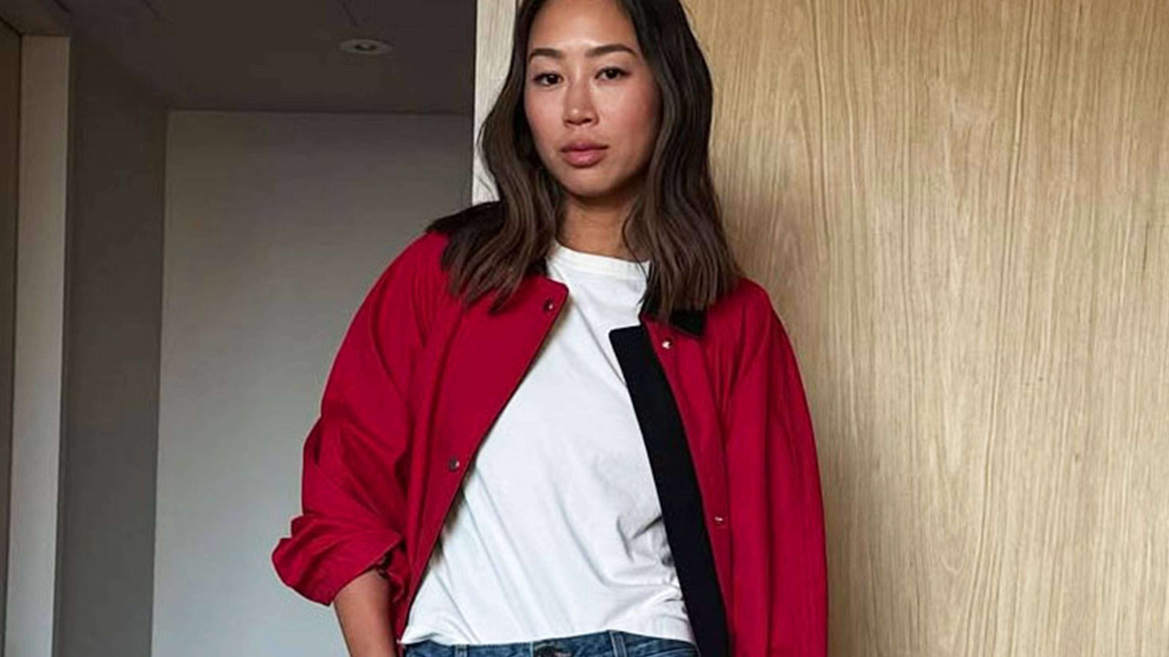 Woman in a red jacket, white t-shirt, and jeans