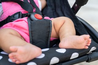 A close up a baby's feat and the safety harness on a pushchair