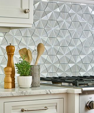 Geo tiles in neutral colorway as backsplash behind hob and marble-top counters.