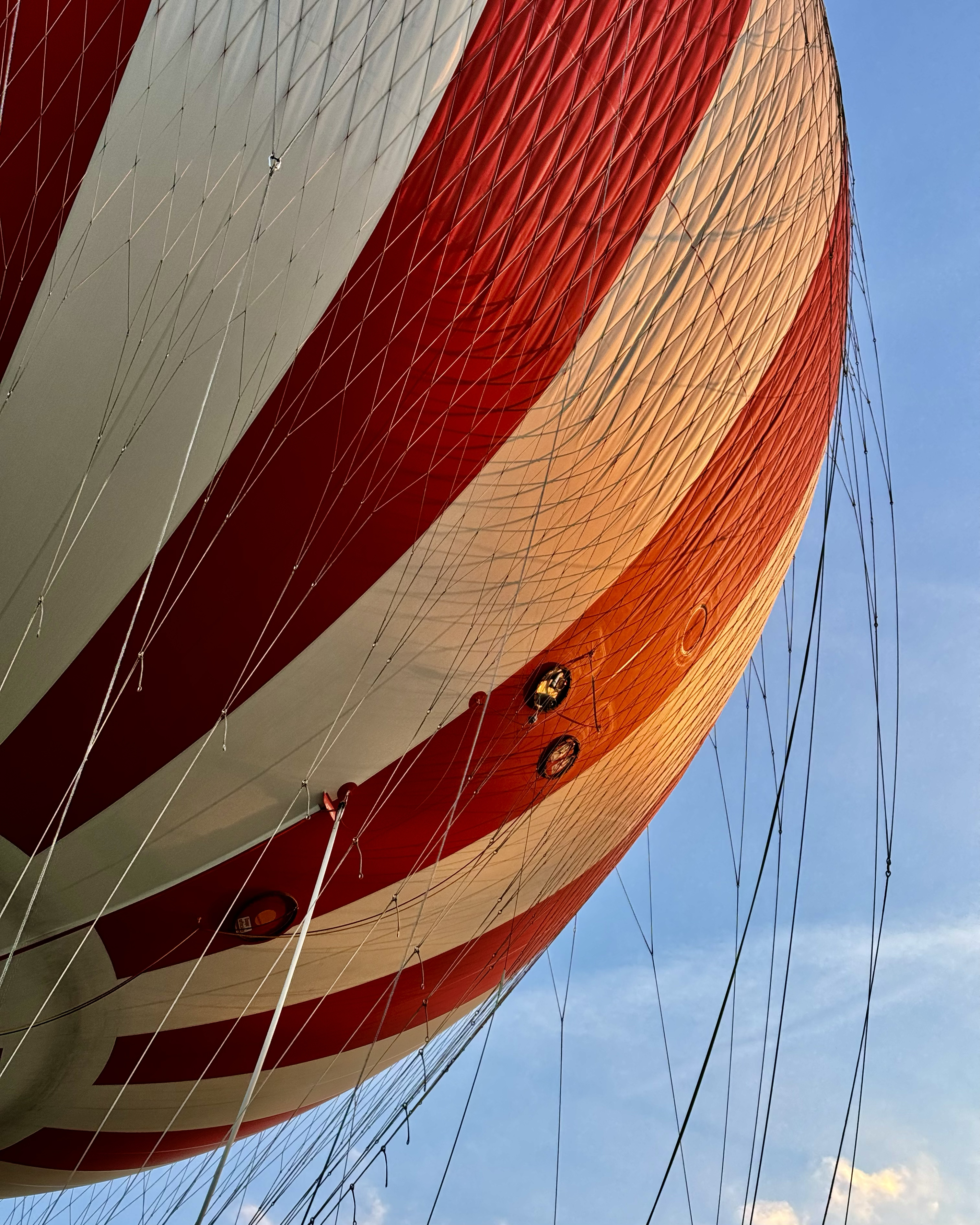 A red and white striped hot air balloon in front of a blue sky