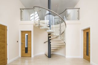Marble spiral staircase by Spiral UK in a double-height entrance hall