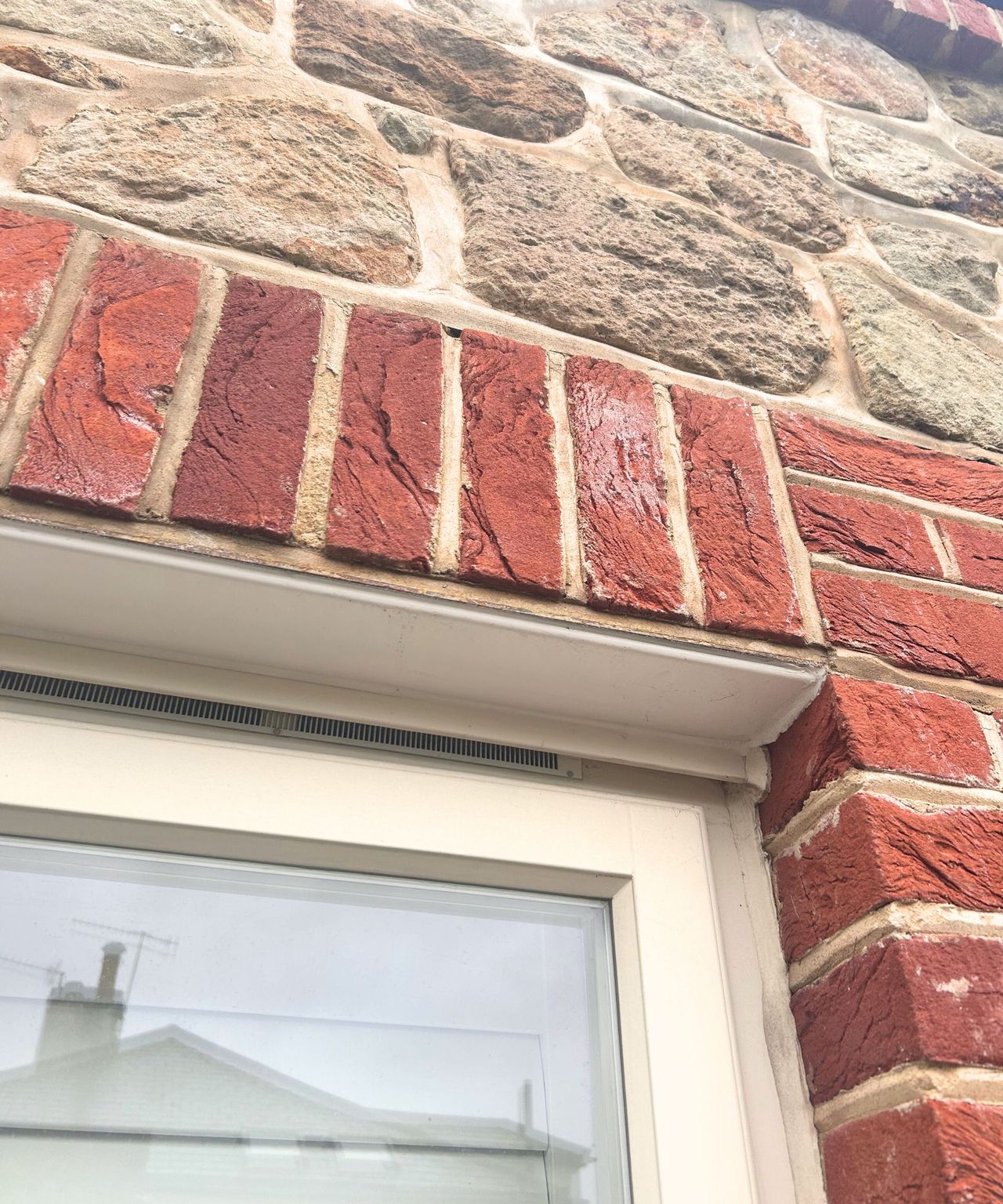 White window with two types of brickwork surrounding it.